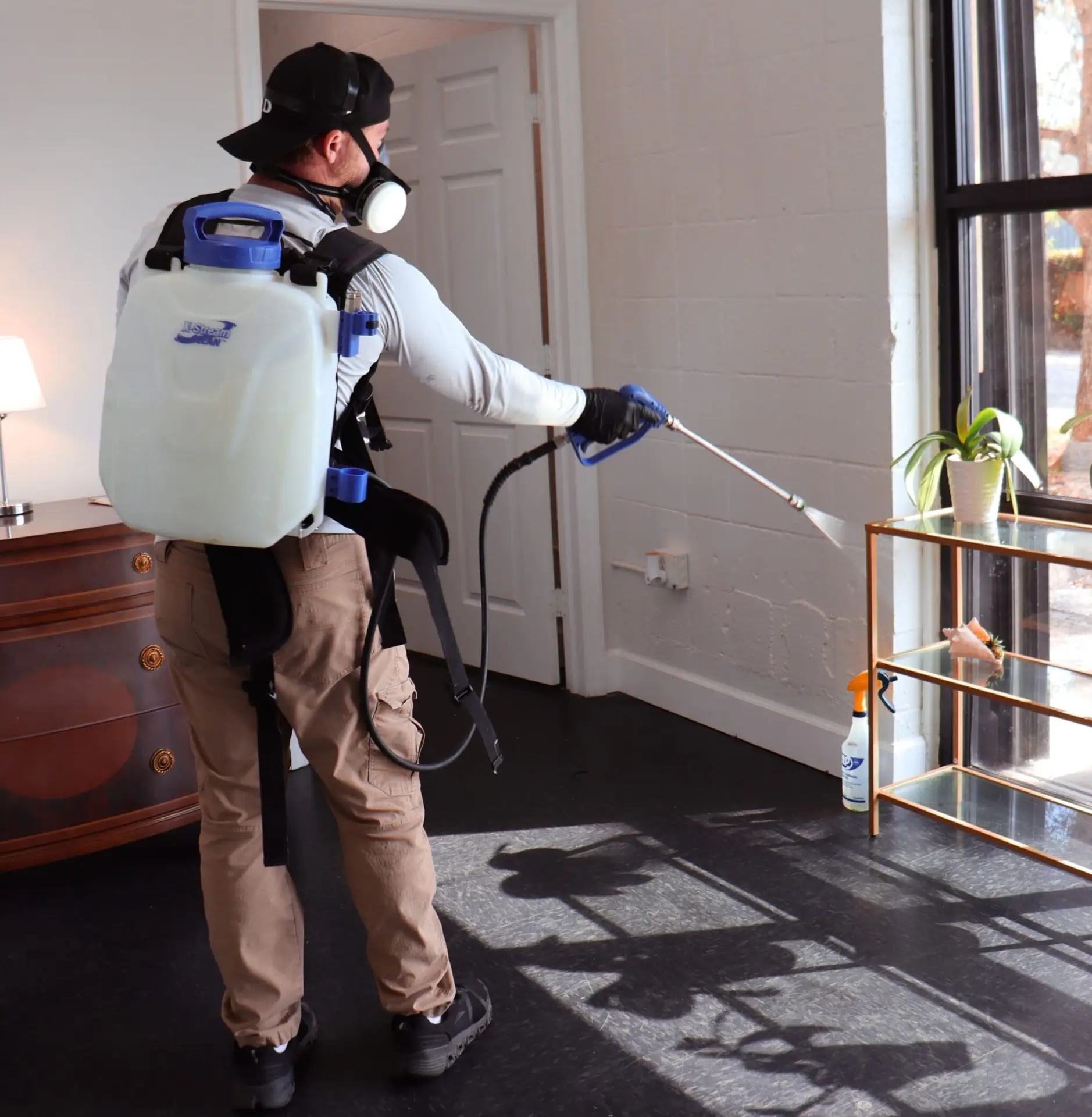 Pest control technician using a backpack sprayer to treat indoor areas for emergency pest infestations, emphasizing rapid response solutions for severe issues in West Palm Beach.