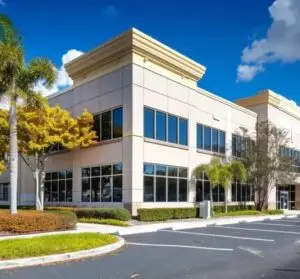 Commercial building exterior with large windows and landscaping, representing Bugsy's Pest Solutions' service areas in Palm Beach and Broward counties.